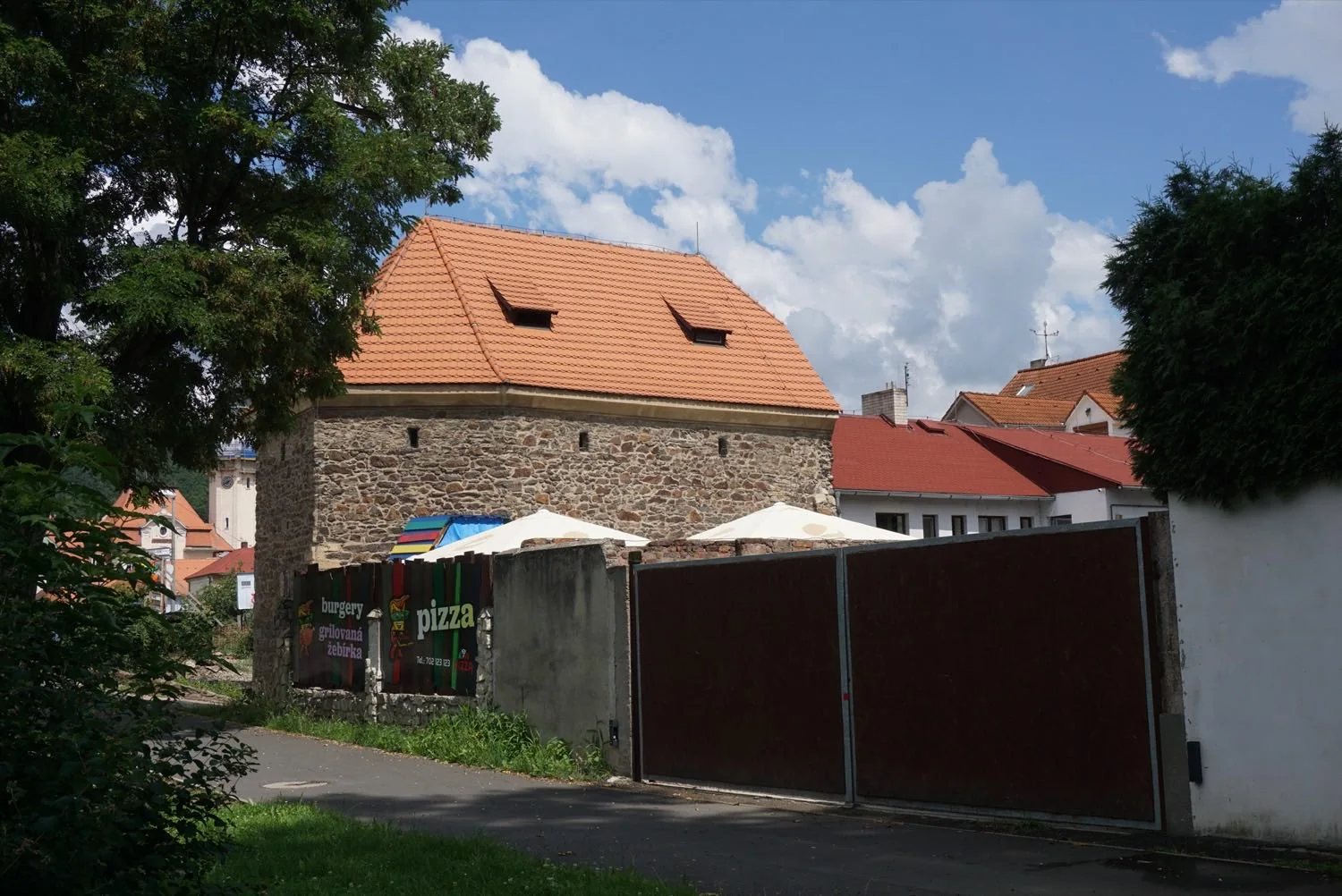 Vjezd do dvora u Husitské bašty v Bílině, pod ní slunečníky restaurace