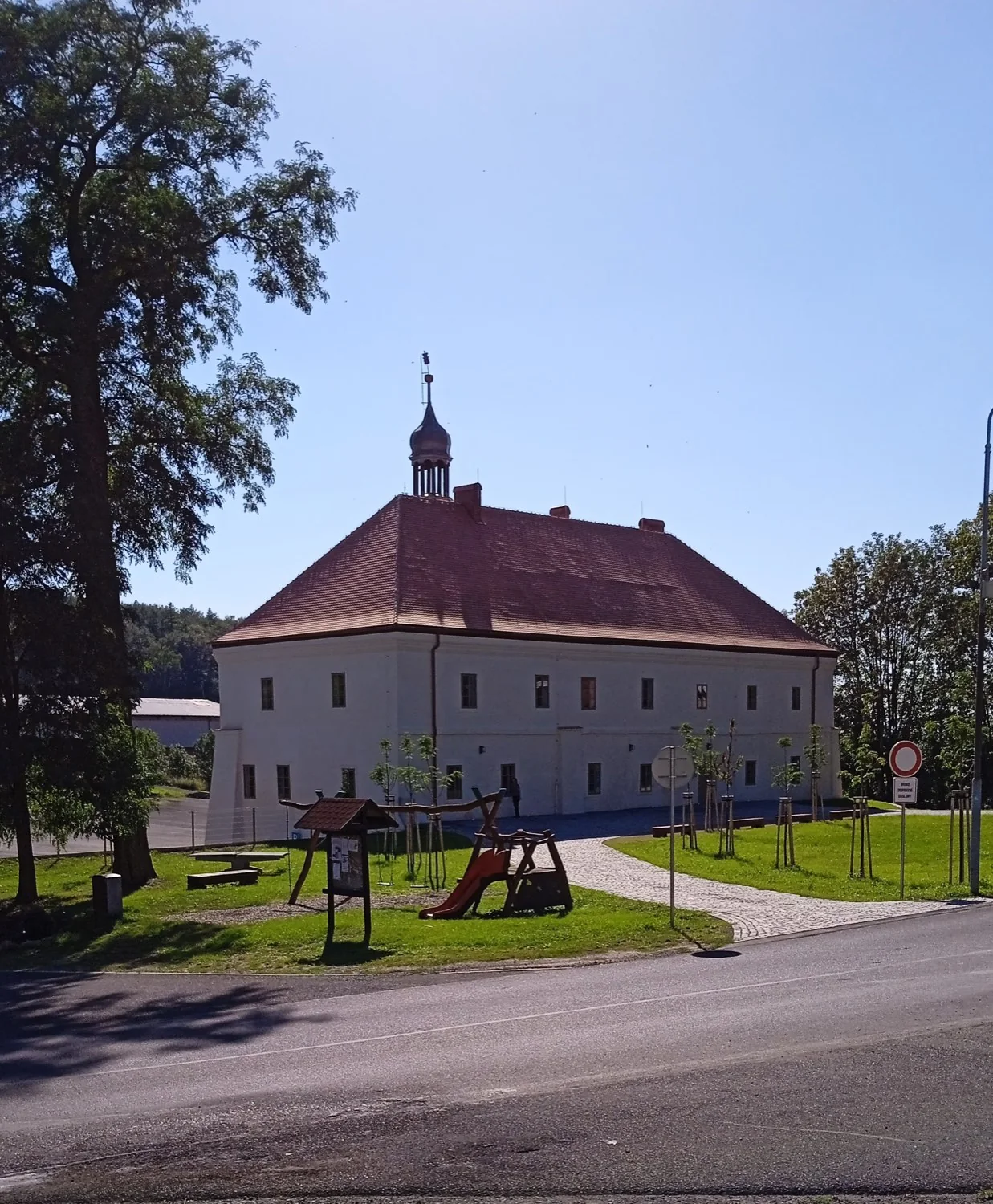 Opravený zámek Mirošovice ve svislém záběru, bílé stěny a věžička