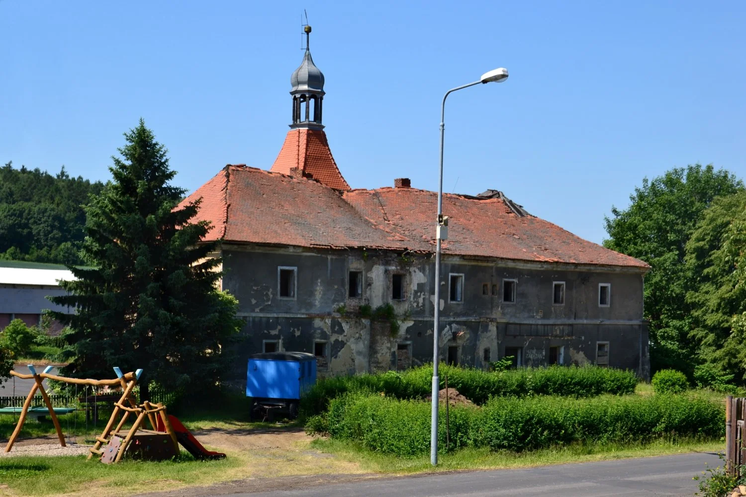 Zámek Mirošovice z návsi před rekonstrukcí, šedá omítka a schátralá střecha