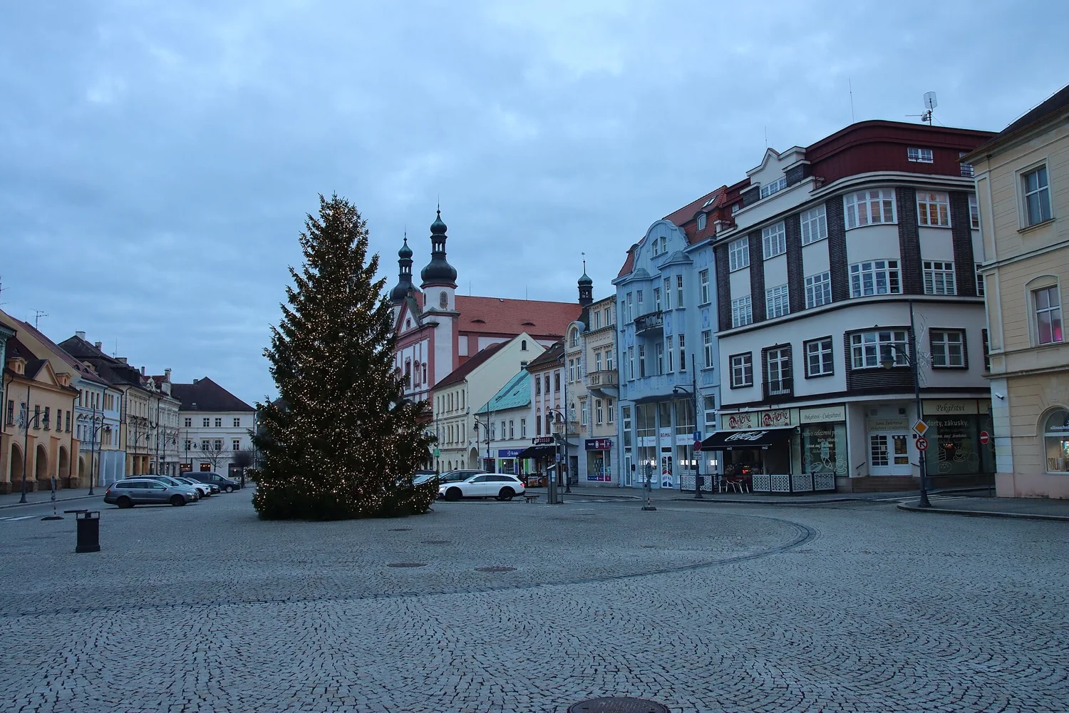 Osvětlený vánoční strom na prázdném náměstí 1. máje v Chomutově za soumraku