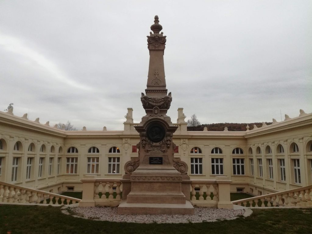 Pomník Reussů před historickou budovou stáčírny Bílinské kyselky v Bílině