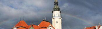 Radnice Bílina s věží a hodinami. Renovace radničních hodin, duha na obloze.