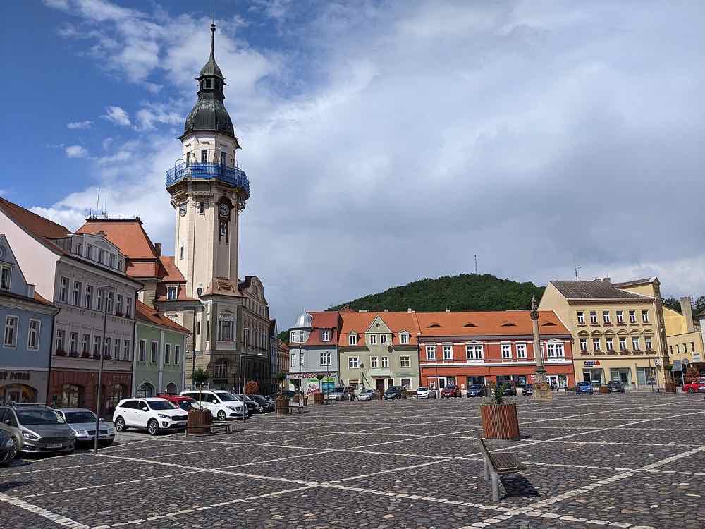 Mírové náměstí in Bílina mit Rathausturm und dem Hügel Chlum im Hintergrund