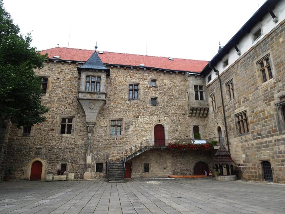 Nádvoří vodního hradu v Budyni nad Ohří s kamennými zdmi, arkýřem a venkovním schodištěm