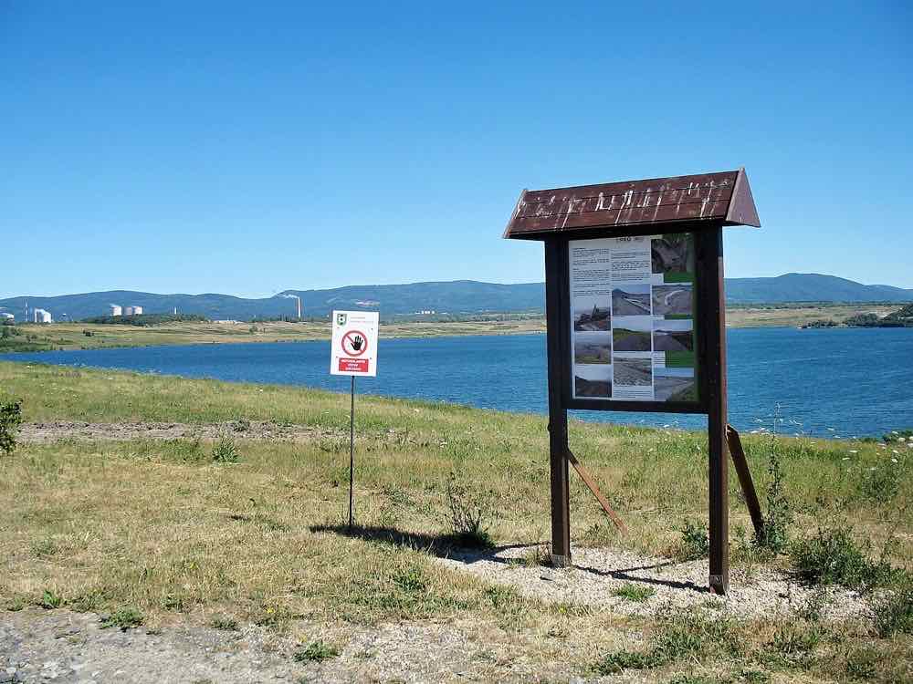 Infotafel am Uferweg des Sees Most mit Blick über das Wasser