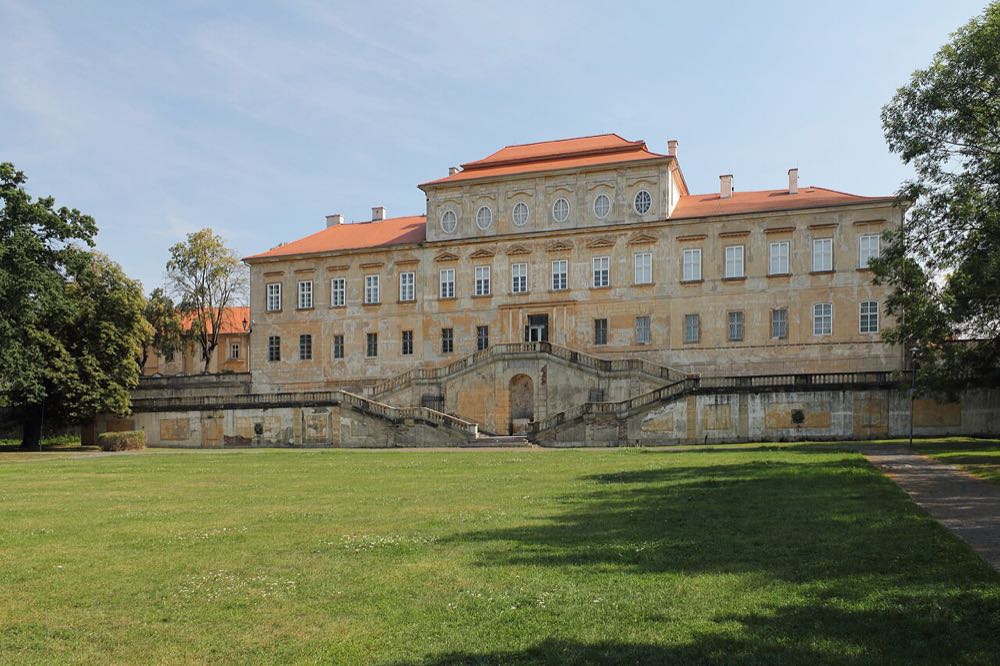 Zahradní průčelí zámku Duchcov s dvouramenným schodištěm a trávníkem zámeckého parku